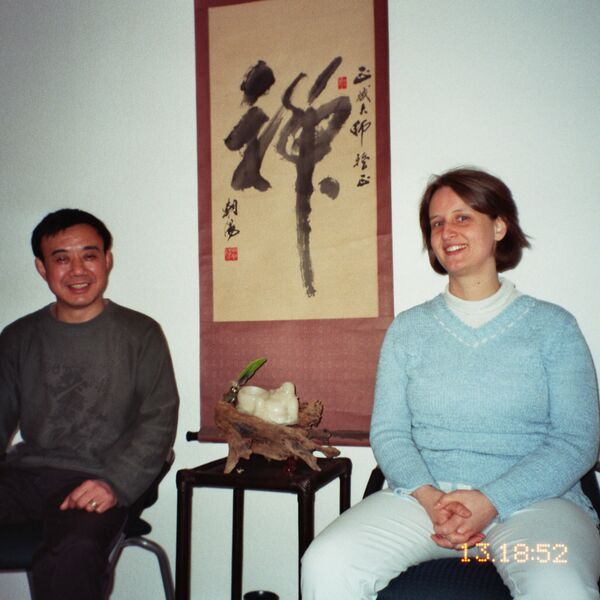 Meister ZHANG Zheng Bin mit Nora Koubek 2006 in ihrer Praxis in Bonn. Zwischen ihnen, eine große chinesische Kalligraphie mit dem Schriftzeichen Chan.
